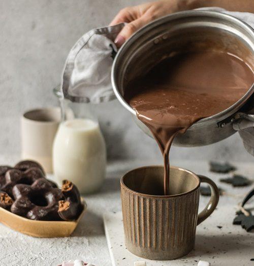 Hands holding a pot of hot chocolate, pouring it into a mug